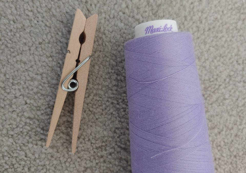 a clothes pin and a spool of purple thread