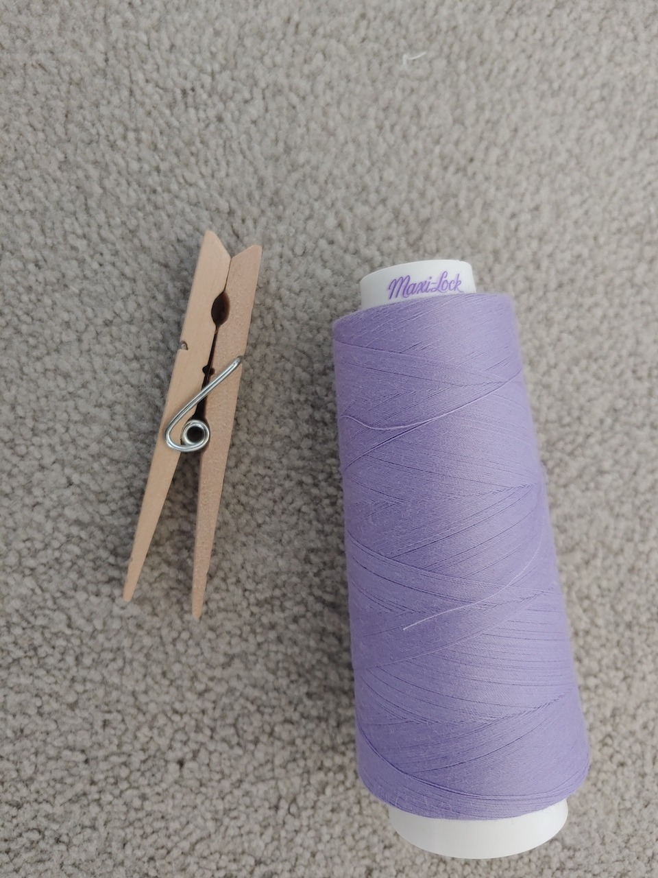 a clothes pin and a spool of purple thread