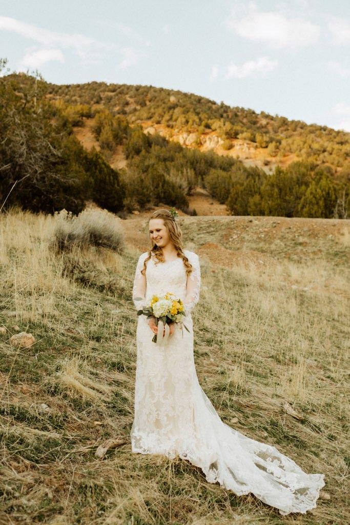 a beautiful bride with a boquet of flowers and a mountain in the background