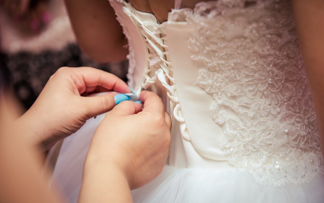 a bridal alteration seamstress lacing up a wedding dress