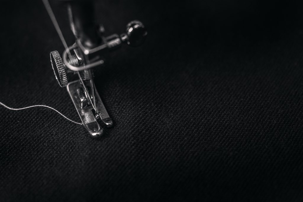 the needle of a sewing machine working on black cloth