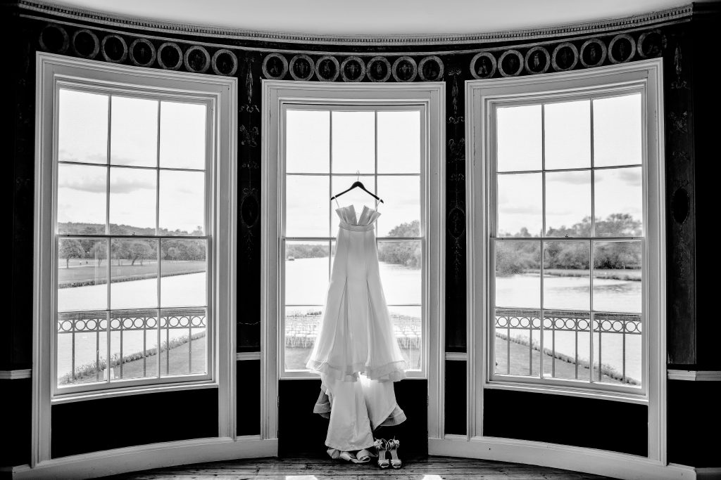 a wedding dress hanging on a window overlooking a snowy landscape