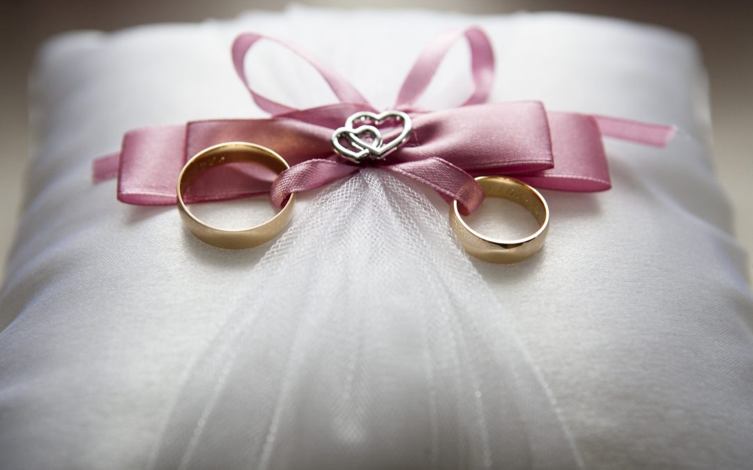 a pink ribbon with hearts and gold rings