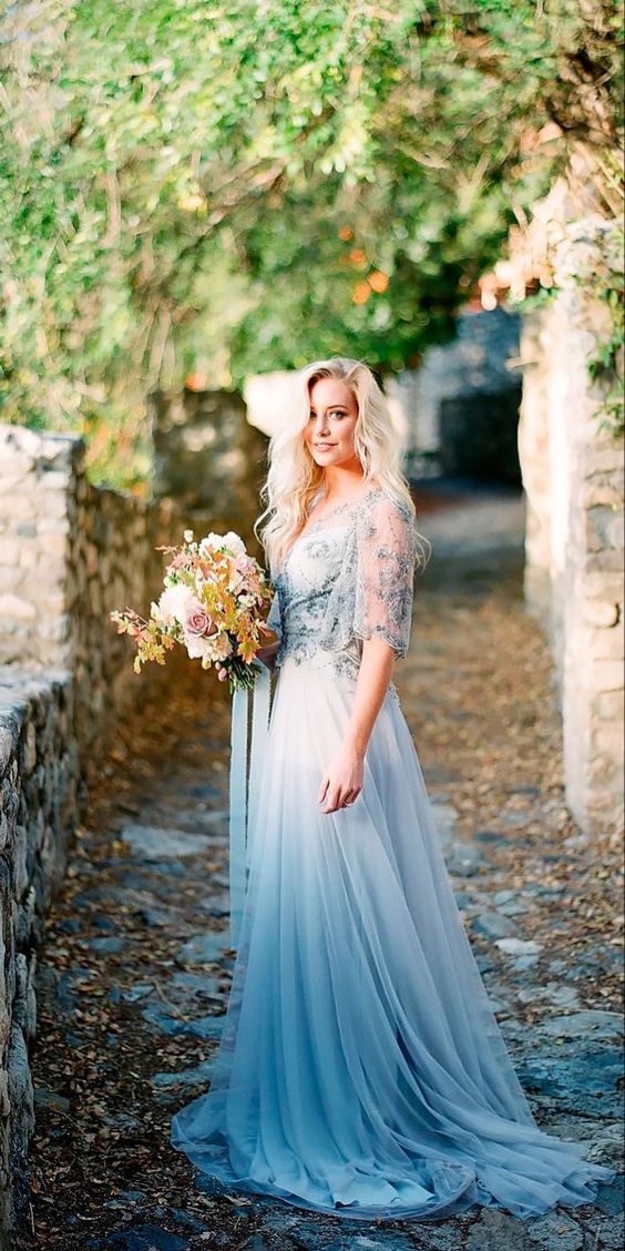 a woman in a blue and white wedding dress holding flowers