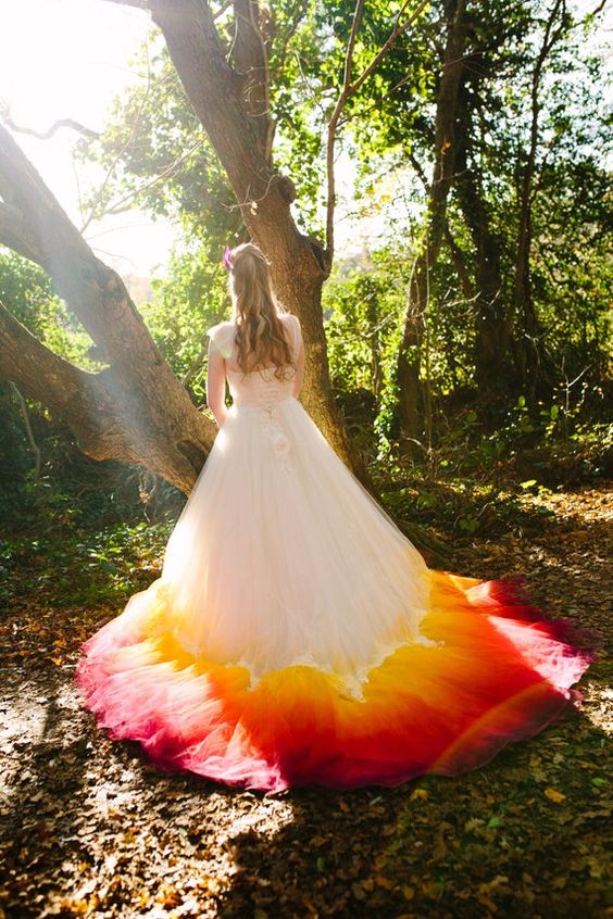 a woman in the forest wearing a white wedding dress with red and yellow skirt